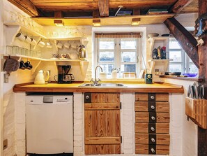 A kitchen with wooden cabinets, a dishwasher, and a window with a view.
