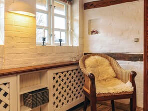 A room with a wicker chair, a window with candles, and a wall with a bicycle drawing.