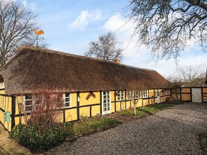 Una casa tradizionale con tetto di paglia, vialetto sterrato e un piccolo giardino.