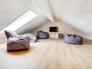 Une chambre située dans un espace de type « loft », avec un plafond en pente, un plancher en bois et un puits de lumière.