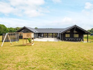 A modern house with a large patio, a swing set, and a covered outdoor seating area. - 5 Star Holiday Home in Sydals (Sydals)