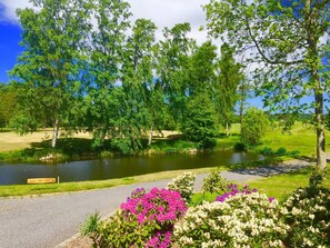 Um parque com lago, árvores e canteiros de flores.