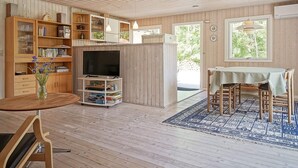 A wooden interior with a dining area, a television on a stand, and a bookshelf. - 4 Star Holiday Home in Nexo (Nexø)