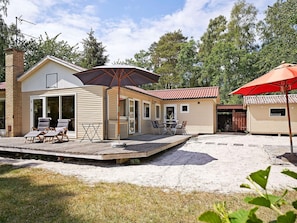 A two-story cabin with a patio area, outdoor seating, and a covered section.