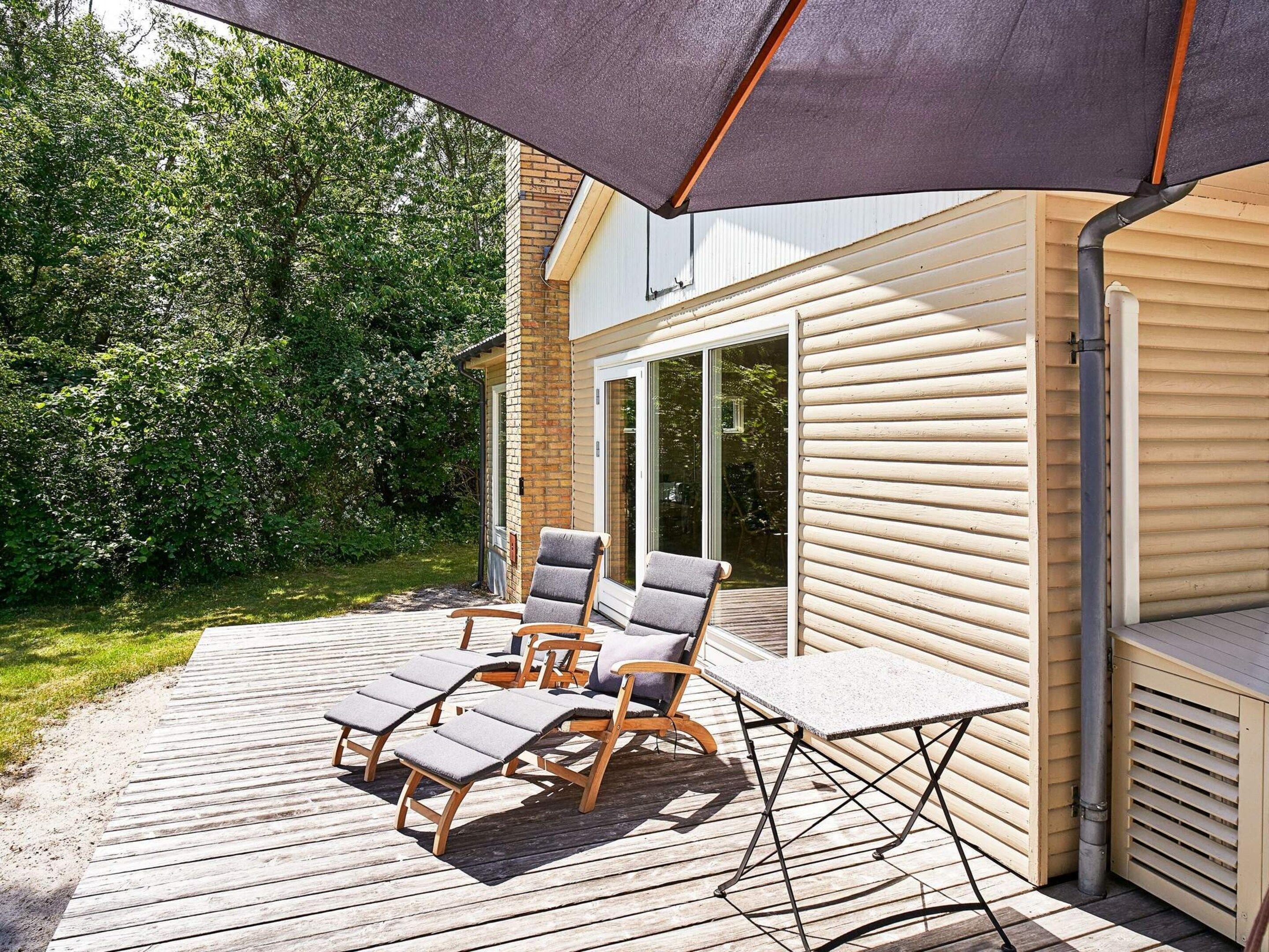 A deck with outdoor furniture, a covered area, and a building with a sliding glass door.