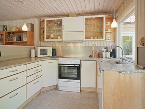 A compact kitchen with white cabinetry, a built-in oven, a microwave, and a sink.