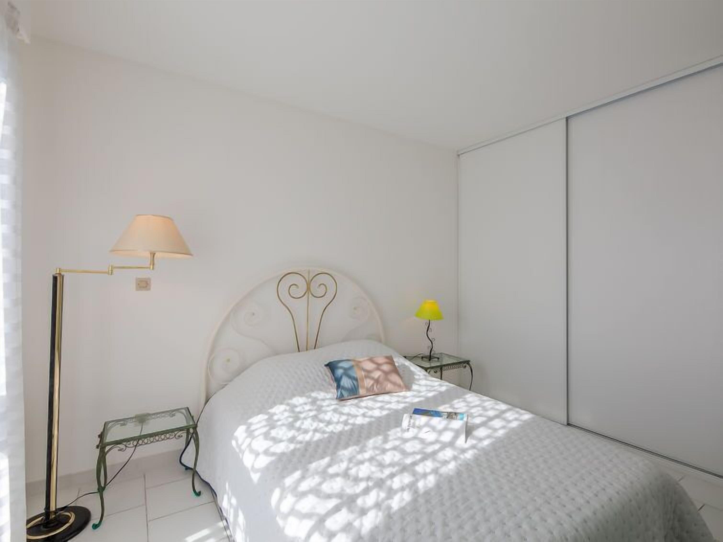 Une chambre à coucher comprenant un lit, une table de chevet, une lampe sur pied et une petite table d’appoint.