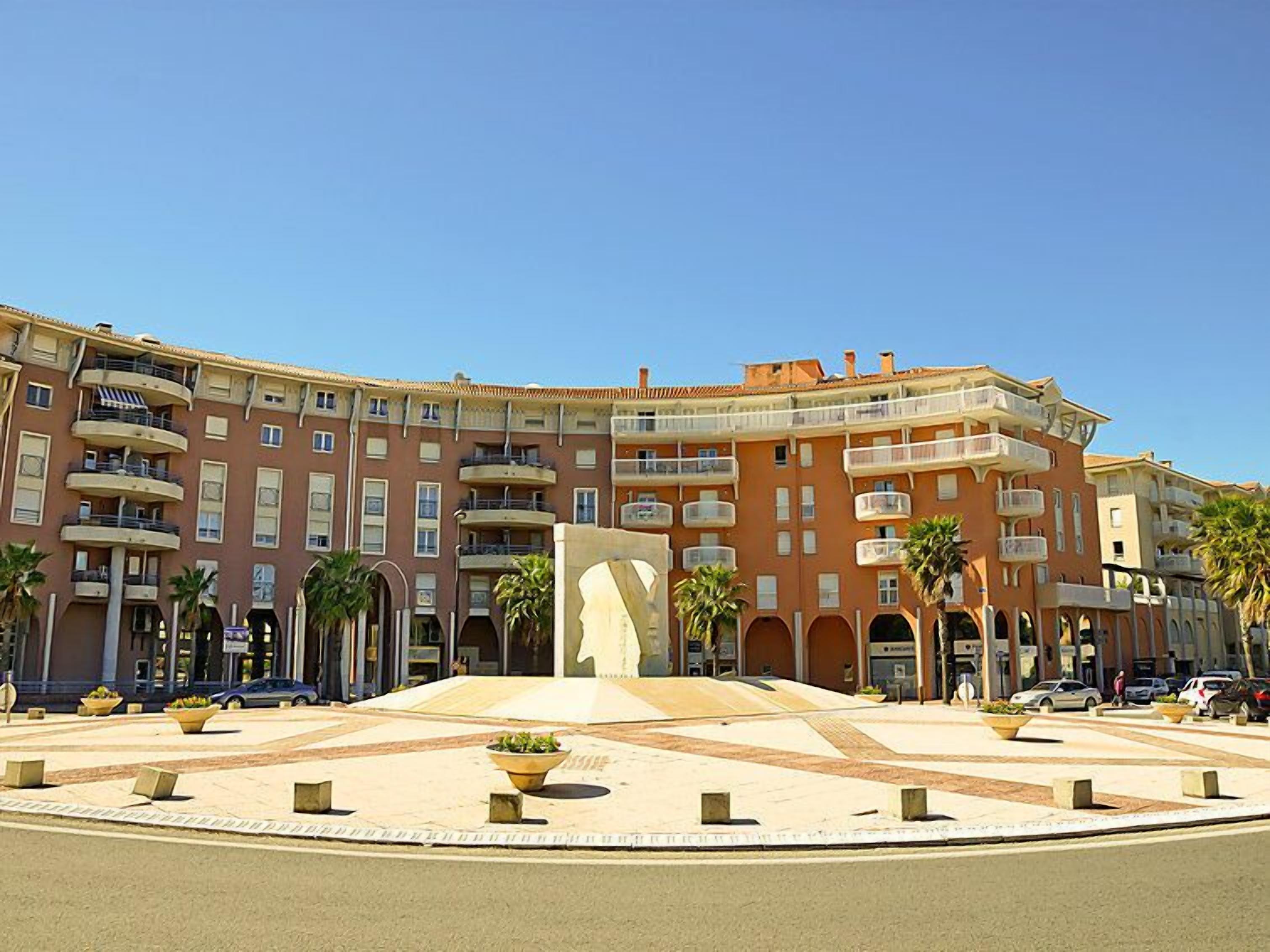 Un hotel de varios pisos con balcones, un patio central y palmeras.