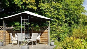 A wooden deck with outdoor furniture and a covered area, surrounded by greenery. - 5 Person Holiday Home in Fiskebackskil-by Traum (Fiskebackskil)