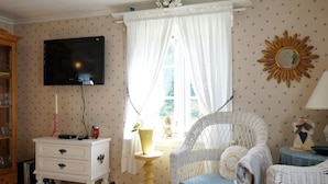 A cozy room with a television, a white wicker chair, a small table, and a decorative mirror. - 5 Person Holiday Home in Fiskebackskil-by Traum (Fiskebackskil)