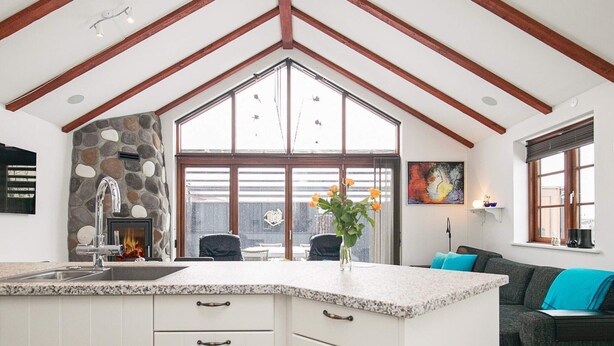 A spacious kitchen with a stone fireplace, a large window, and a cozy seating area with a sofa and a coffee table. - 4 Person Holiday Home in Esbjerg V (Esbjerg)