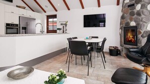 A modern kitchen with white cabinets, stainless steel appliances, and a stone fireplace. - 4 Person Holiday Home in Esbjerg V (Esbjerg)