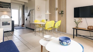 A modern living room with a dining area, a kitchen with a built-in oven, and a TV mounted on the wall. - 6 Person Holiday Home in Hadsund (Hadsund)