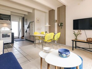 A modern living room with a dining area, a kitchen with a built-in oven, and a TV mounted on the wall. - 6 Person Holiday Home in Hadsund (Hadsund)
