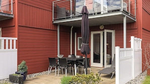 A red house with a balcony, a table with chairs, and potted plants. - 6 Person Holiday Home in Hadsund (Hadsund)