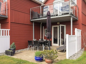 A red house with a balcony, a table with chairs, and potted plants. - 6 Person Holiday Home in Hadsund (Hadsund)