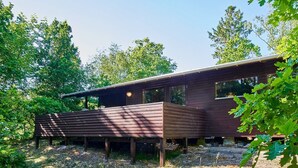 A modern wooden cabin with a flat roof, large windows, and a deck area. - 4 Person Holiday Home in Aakirkeby (Akirkeby)