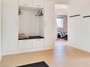 Habitación con armario empotrado, un banco con cojín y cama con colcha a cuadros.
