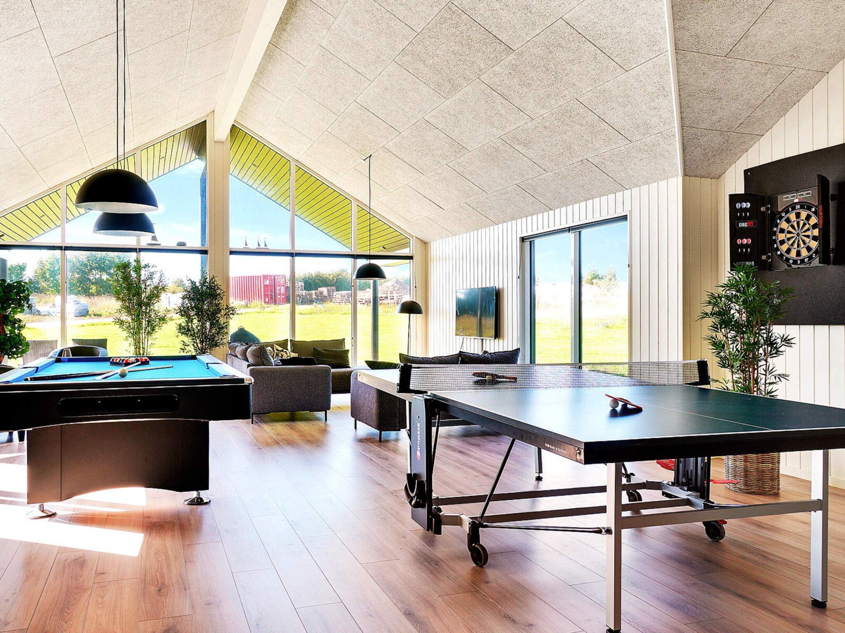 Een ruime binnenzone met een pooltafel, een tafeltennistafel en een dartbord.