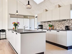 A modern kitchen with a central island, white cabinetry, a black countertop, and a tiled backsplash. - 5 Star Holiday Home in Sydals (Sydals)