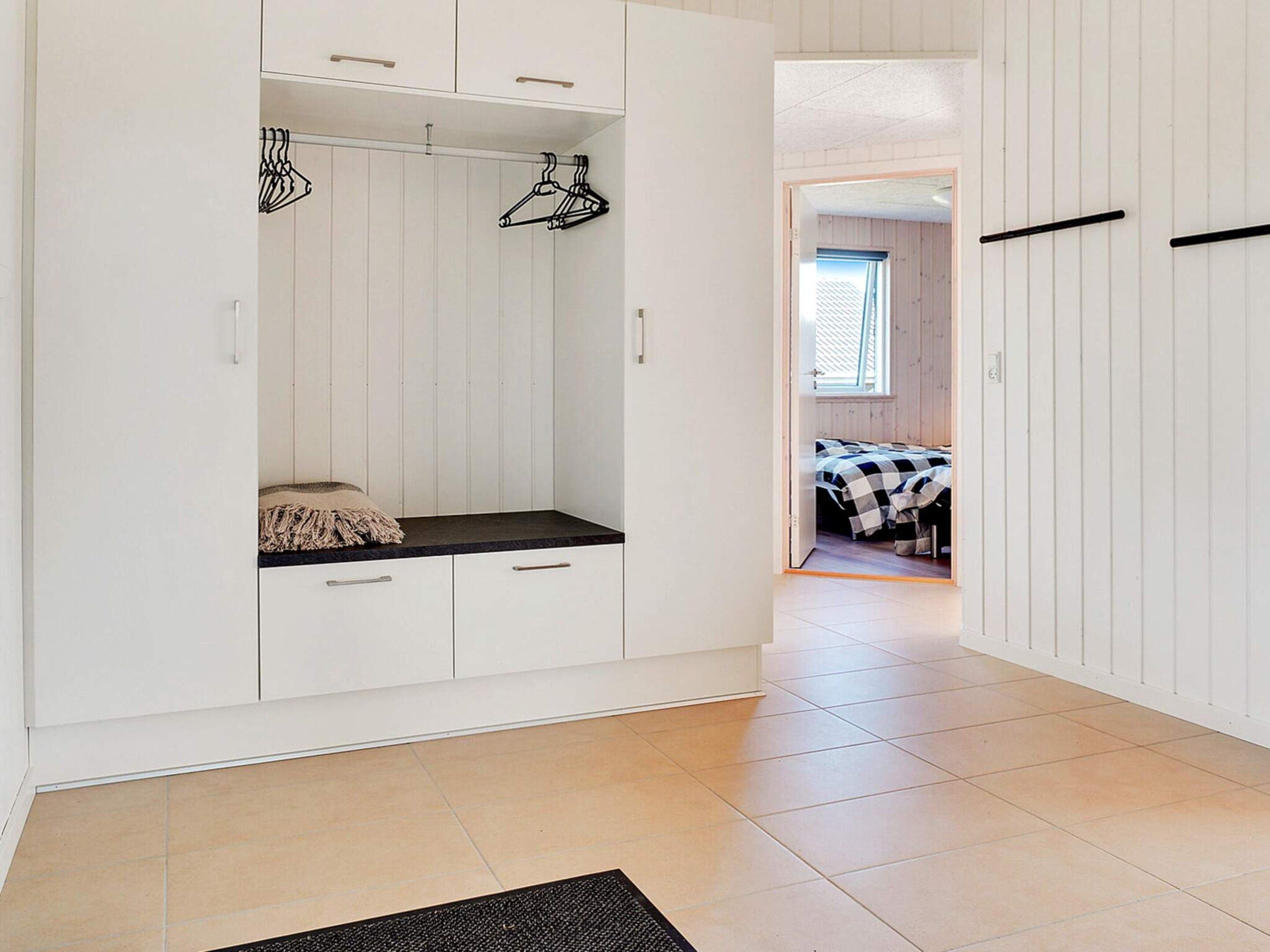 Ein Zimmer mit integriertem Kleiderschrank, einer Sitzbank und einem Bett mit karierter Bettdecke.