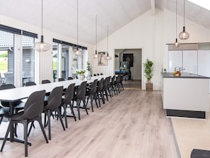 A modern dining area with a long table, chairs, pendant lights, and a kitchen island.