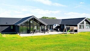 A modern building with a glass facade, outdoor seating area, and a green slide.
