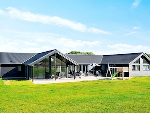 A modern building with a glass facade, outdoor seating area, and a green slide. - 5 Star Holiday Home in Sydals (Sydals)