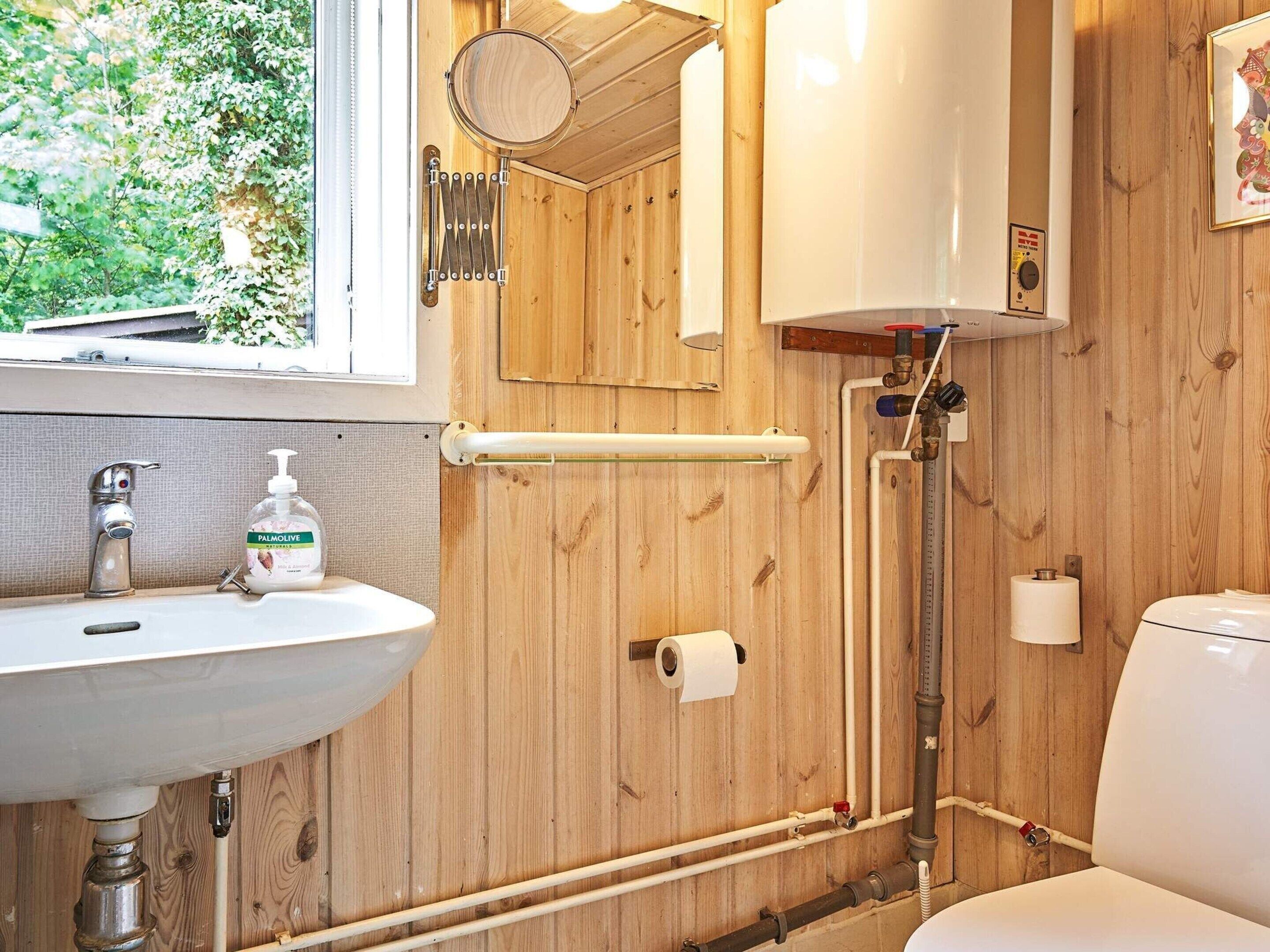Un baño con paneles de madera, un lavabo, inodoro y ducha.