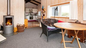 A cozy cabin interior with a wood-burning stove, a dining area, and a kitchen.