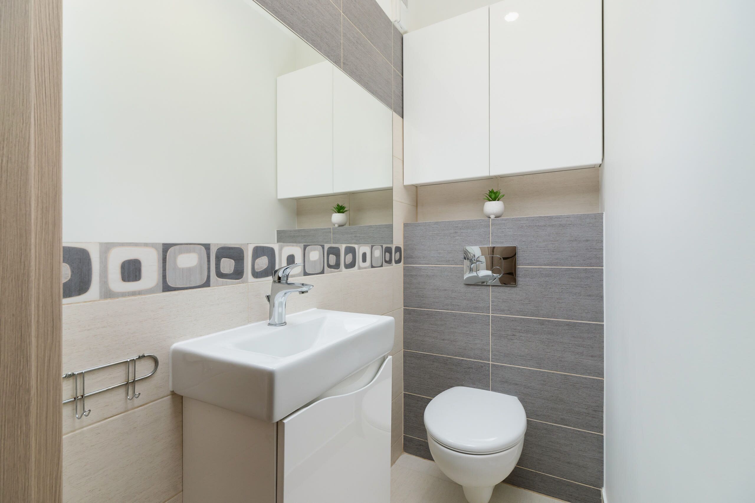 Een moderne badkamer met een witte wastafel, toilet en kastjes.