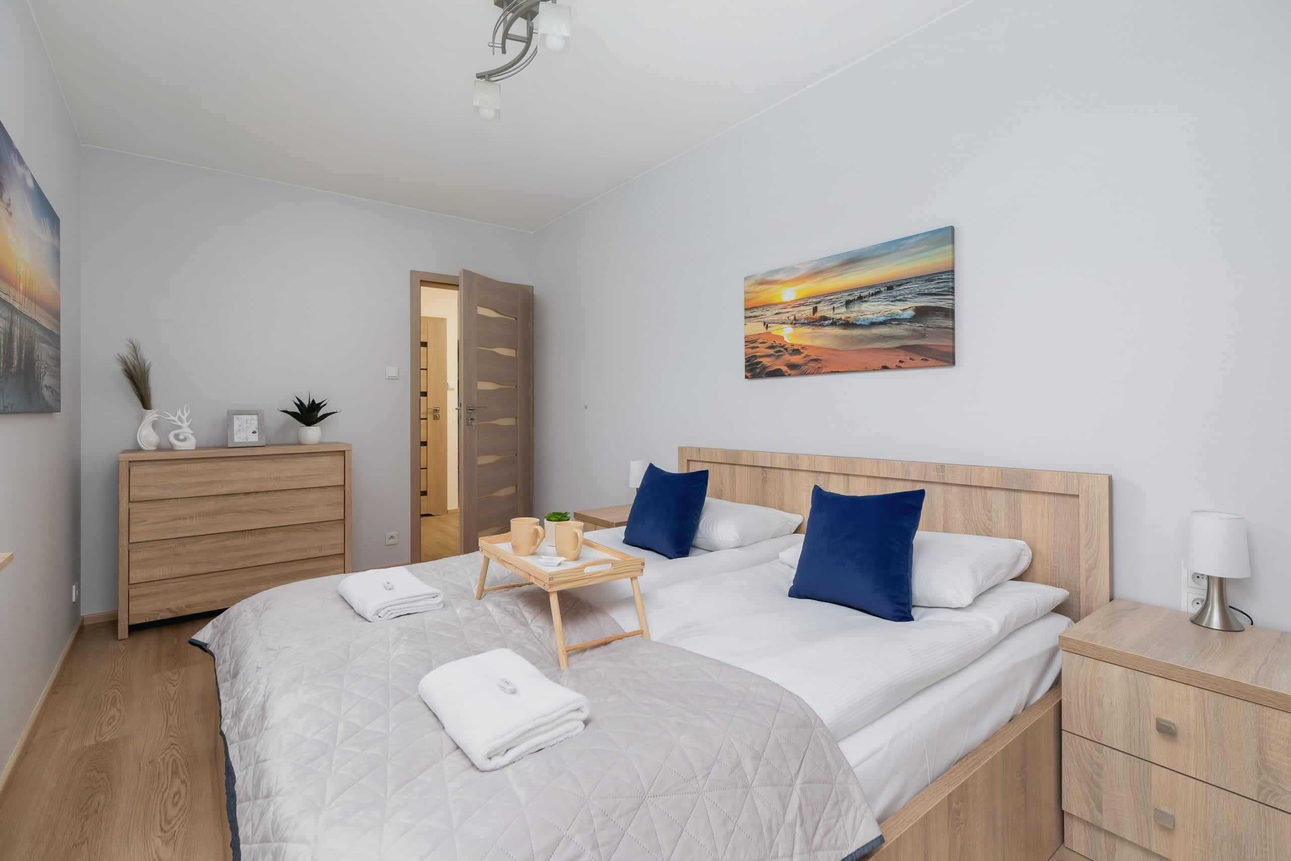 Een hotelkamer met een bed, nachtkastjes, een dressoir, een schilderij en een deur.