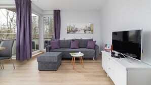 A modern living room with a grey sectional sofa, a flat-screen TV, and a small white table.