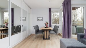 A modern room with a dining table, chairs, a sofa, and a large window with curtains.