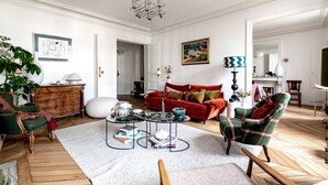 Ein Wohnzimmer mit rotem Sofa, grünem Sessel und Couchtisch mit Büchern und Dekoration.