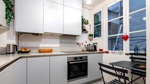 Eine moderne Küche mit weißen Schränken, einem Einbauofen und einem Fenster mit Herz-Dekoration.