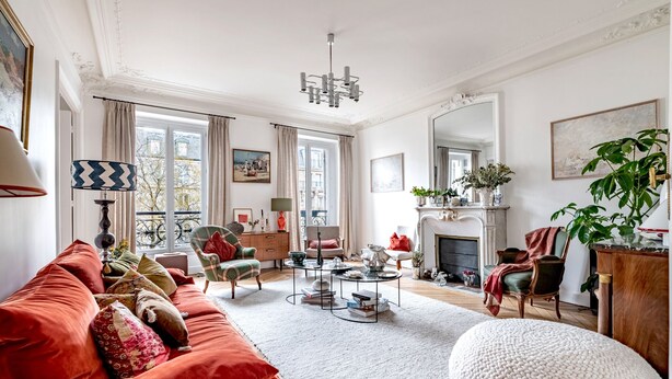 Ein geräumiges Wohnzimmer mit einem roten Sofa, einem weißen Teppich und einem Kamin.