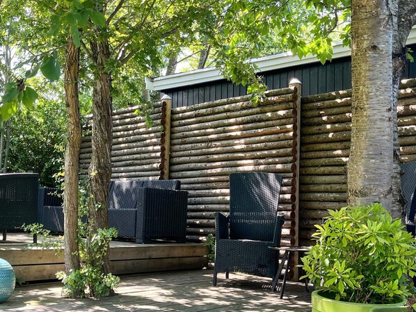 An outdoor seating area with wicker chairs and a wooden deck.