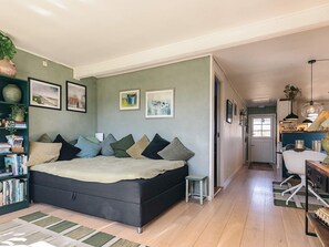 A spacious bedroom with a large bed, a bookshelf, and a desk area.