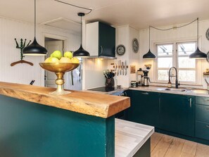 A kitchen with wooden countertops, a bowl of fruit, hanging knives, and a coffee machine.