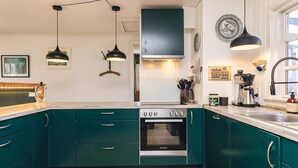 A kitchen with teal cabinets, a stove, and pendant lights. - 8 Person Holiday Home in Gilleleje-by Traum (Gilleleje)