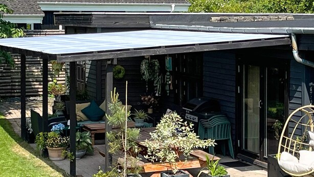 An outdoor patio area with a covered seating area, potted plants, and a hanging chair. - 8 Person Holiday Home in Gilleleje-by Traum (Gilleleje)