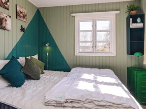 A bedroom with a bed, a window, and a green dresser.