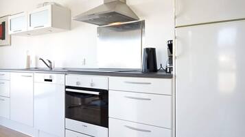 Una cocina moderna con armarios blancos, un horno Bosch, una campana extractora de acero inoxidable y una cafetera sobre la encimera.