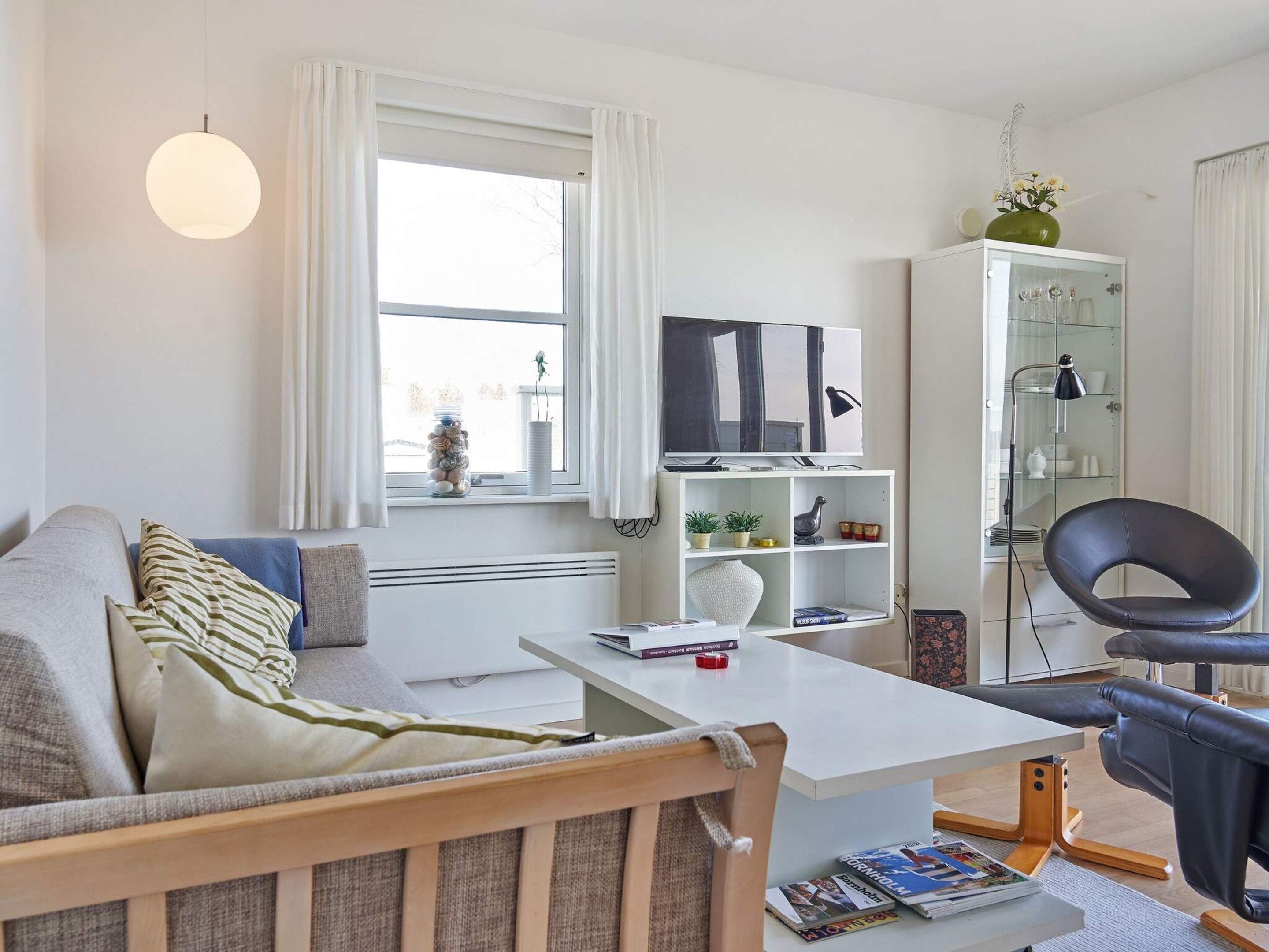 Una sala de estar moderna con un sofá, una mesa de centro, un televisor y un armario.