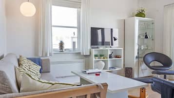 Una sala de estar moderna con un sofá, una mesa de centro, un televisor y un armario.