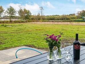 Ein Essbereich im Freien mit einem Tisch für zwei Personen, einschließlich einer Weinflasche, zwei Gläsern und einer Vase mit Blumen.