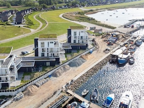 An aerial view of a coastal area with modern buildings, a marina with boats, and a curved road. - 5 Star Holiday Home in Wendtorf (Wendtorf)