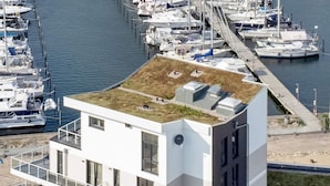 A modern building with a flat roof, large windows, and a marina in the background. - 5 Star Holiday Home in Wendtorf (Wendtorf)