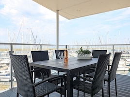En terrasse med et bord og stole, med udsigt over en lysthavn med mange både.